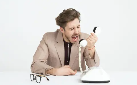 Mężczyzna w garniturze krzyczy do telefonu, jego twarz wyraża złość. Widać, że jest cholerykiem.