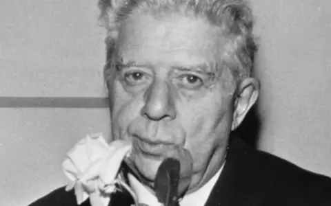 Un uomo con una rosa bianca al bavero, come se "ho sceso dandoti il braccio" fosse un ricordo dolce.