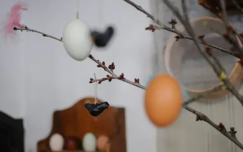 Påskris med ägg och små fåglar av papier maché. En rosa fjäder sticker upp.