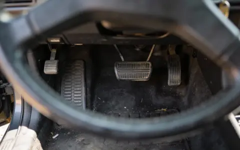 Widok na pedały samochodu. Sprzęgło, hamulec i gaz. Uważaj na jazdę na półsprzęgle, bo to męczy auto.