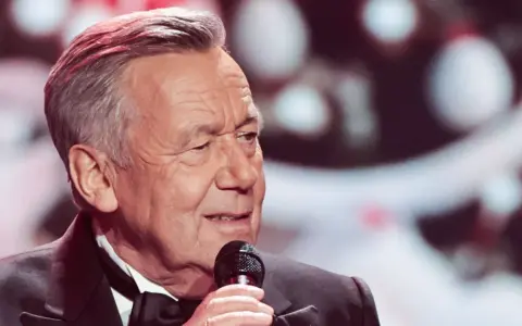 Roland Kaiser singt mit Mikrofon, im Anzug mit Fliege.