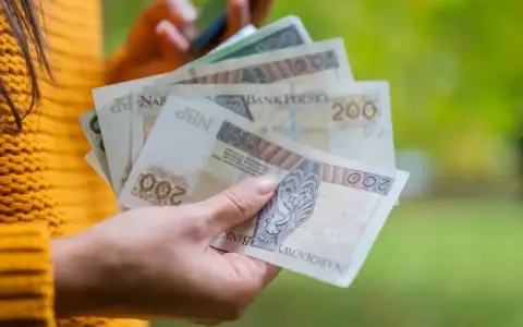 Dłoń trzyma polskie banknoty 200 zł, które mogą stanowić ekwiwalent za urlop.