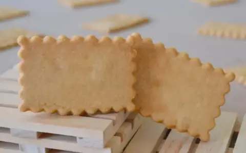 Deux biscuits rectangulaires aux bords festonnés, parfaits pour une recette biscuit personnalisé. Ils reposent sur des petites palettes en bois.