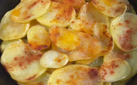 Rodajas de patatas fritas al horno, doradas y espolvoreadas con pimentón.