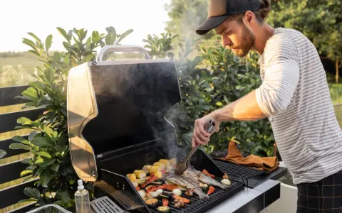Mężczyzna grilluje ryby i warzywa na grillu gazowym, pokazując, jak działa grill gazowy.