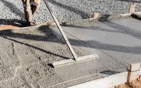 Un ouvrier lisse le béton frais pour créer une pente de terrasse.