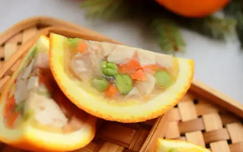Galaretka z kurczaka z warzywami, podana w połówkach pomarańczy, wygląda apetycznie.
