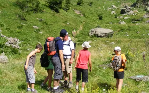 Famille en randonnée facile dans les Pyrénées, profitant d'un paysage verdoyant et rocheux.