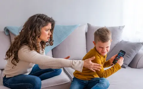 Genervte Mutter streitet mit Sohn, der sein Handy nicht abgeben will. Mögliche ADHS-Erziehungsfehler im Fokus.