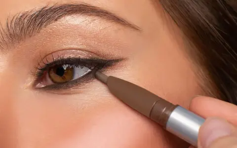 Ojo marrón con delineado invertido, aplicando lápiz marrón en la línea de agua inferior para un look dramático.