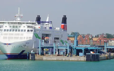 Prom Skania cumuje przy nabrzeżu. Statek pasażerski z zielonymi akcentami i czerwonymi kominami czeka na załadunek.