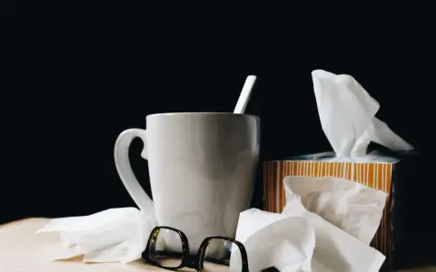 Kubek z herbatą, chusteczki i okulary. Urlop L4 nie zawsze jest wypoczynkiem.
