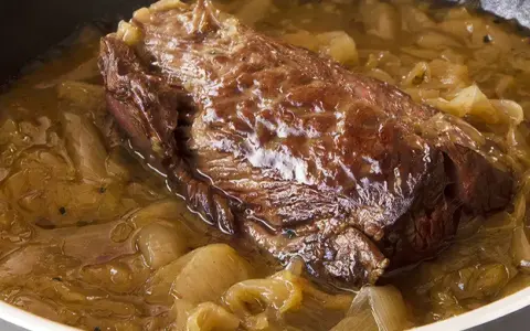 Une succulente buche d'onglet mijote dans une sauce aux oignons caramélisés, prête à être dégustée.