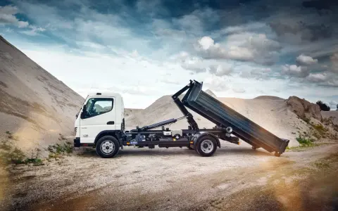 Biały Mitsubishi Canter z podniesioną skrzynią ładunkową na tle żwirowych hałd.