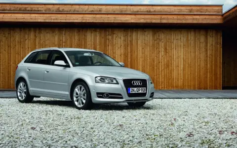 Silberner Audi A3 Baujahr 2008 steht auf einem Kiesparkplatz vor einer Holzwand.
