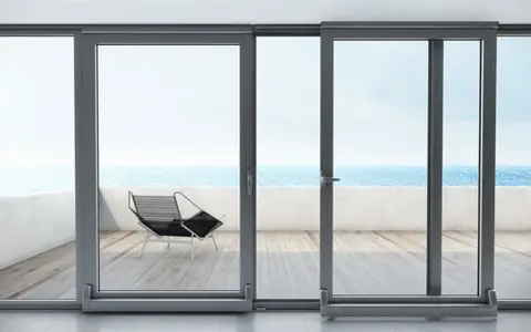 Ventanas osciloparalelas con vista al mar. Un sillón moderno en la terraza de madera.