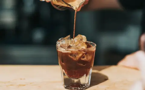 Ein Espresso fließt in ein Glas mit Eiswürfeln. Ist kalter Kaffee gesund? Diese Erfrischung könnte eine Antwort sein.