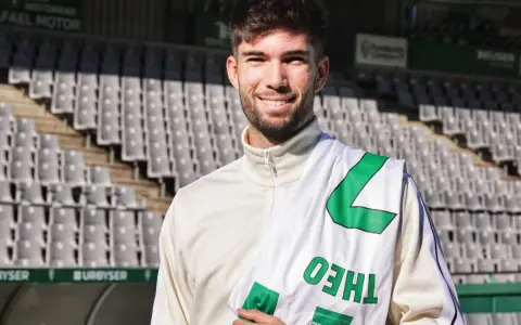 Théo Zidane sonríe con una bufanda del equipo en el estadio.