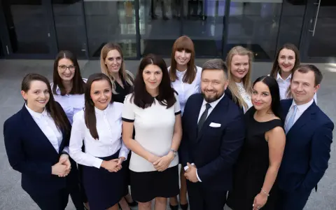 Grupa prawników w garniturach i strojach biznesowych pozuje przed budynkiem.