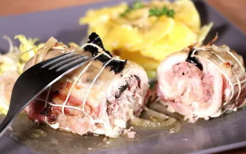 Une cuisse de poulet farcie, savoureusement roulée et ficelée, attend d'être dégustée avec une garniture de pommes de terre.