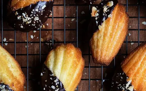 Des biscuits madeleine au chocolat, parsemés d'éclats d'amandes, refroidissent sur une grille. Un délice gourmand !