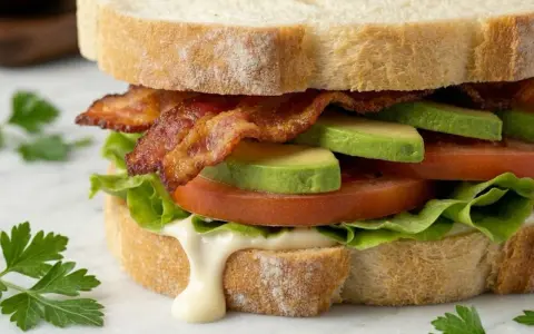 Ein BLT-Sandwich mit knusprigem Speck, saftigen Tomaten, cremigem Avocado und knackigem Salat auf getoastetem Brot.