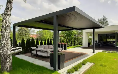 Nowoczesna pergola z wygodną sofą i stolikiem to idealne miejsce do wypoczynku. Zastanawiasz się, co położyć na taras? Tutaj widzisz gotową aranżację.