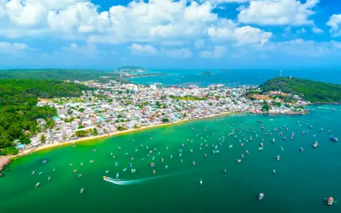 Luftaufnahme einer Küstenstadt mit vielen Booten im türkisfarbenen Meer. Perfekt für die phu quoc beste reisezeit.