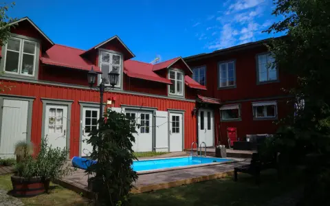 Rött hus med vita fönsterluckor och en blå pool. Kanske finns det tre små rum därinne, redo för gäster.
