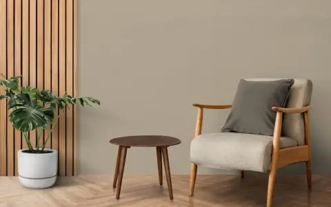Wnętrze w odcieniu taupe jaki to kolor, z fotelem, stolikiem i rośliną.