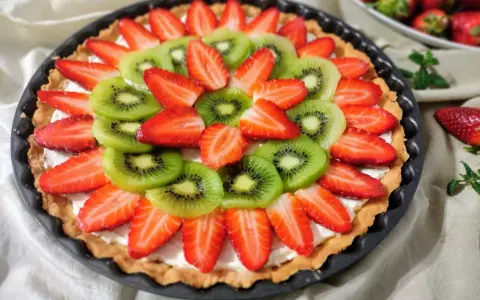 Kolorowa tarta z owocami: plasterki kiwi i truskawek ułożone na kremowym nadzieniu.