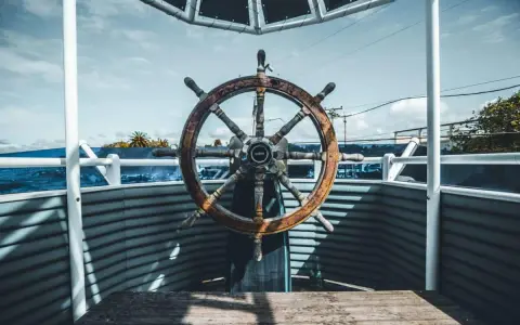 Roue de gouvernail en bois patiné, prête à barrer un bateau vers l'horizon bleu.