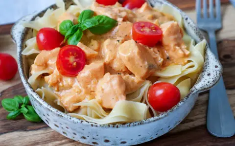 Schmackhafte Nudeln mit Lachs in cremiger Sauce, garniert mit Kirschtomaten und Basilikum. Ein Genuss!