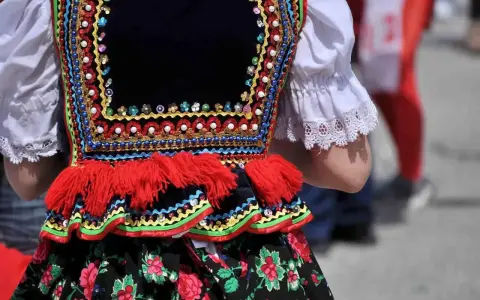 Kolorowy strój ludowy, ozdobiony koralikami i haftem, zapowiada radosne tańce ludowe.