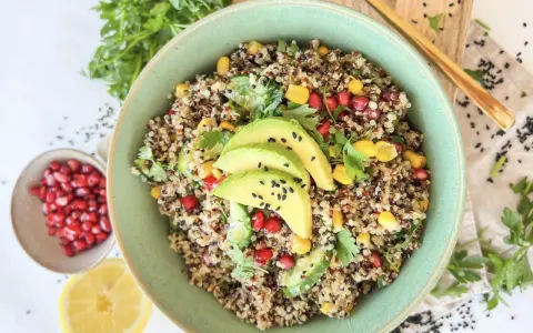 Bunter Quinoa Salat mit Avocado, Granatapfelkernen, Mais und frischer Petersilie. Ein gesundes und leckeres Gericht.