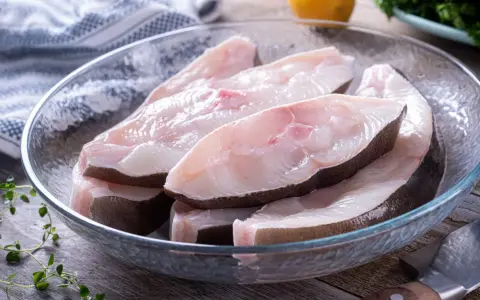 Świeże kawałki halibuta w szklanej misce, gotowe do przyrządzenia. Zapach halibuta na jakie ryby?