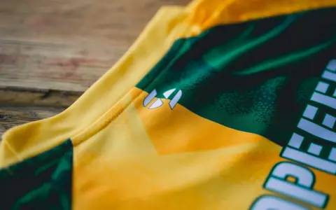 Nahaufnahme eines gelb-grünen **jersey polyester** mit einem weißen Logo.