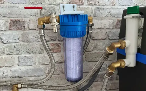 Système de filtration d'eau avec cartouche visible, raccordé à un adoucisseur. Un filtre avant adoucisseur obligatoire pour une eau pure.