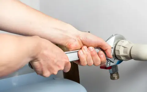 Mains d'un technicien serrant un raccord de tuyau lors d'un entretien adoucisseur d'eau Culligan.