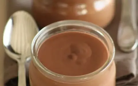 Un pot de crème chocolat onctueuse, prêt à être dégusté avec une cuillère.