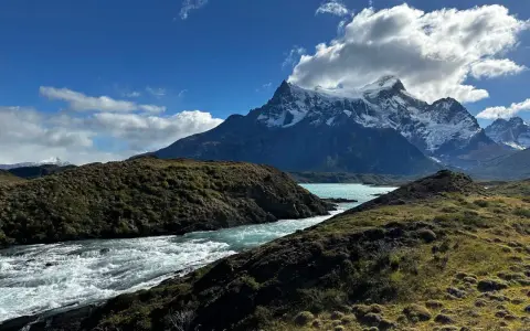 Wodospad w **Torres del Paine** z turkusową wodą i ośnieżonymi szczytami w tle.