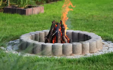 Eine Feuerstelle mit gemauerten Steinen und loderndem Feuer im Garten.