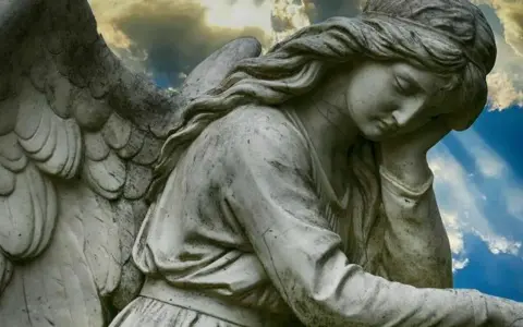 Kamienna rzeźba anioła zamyślonego pod niebem. 1333 znaczenie tego widoku może być symbolem nadziei.