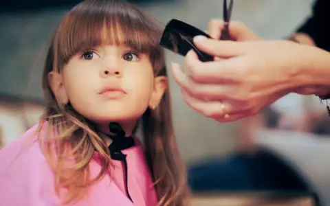Ein **Kind** bekommt einen neuen **Pony schneiden** im Friseursalon.