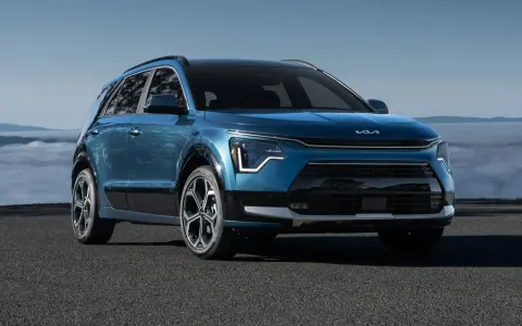 Niebieski Kia Niro Hybrid z nowoczesnym designem, zaparkowany na tle mglistego krajobrazu.