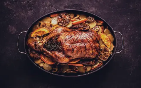 Brathähnchen mit Kartoffeln, Karotten, Orangen und Knoblauch. Ein Festmahl, das perfekt zu einem Glas Wein zu Ente passt.