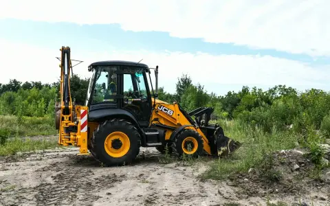 Żółta koparko-ładowarka JCB 4CX na placu budowy. Maszyna gotowa do pracy, a jej spalanie jest optymalne dla tego typu zadań.