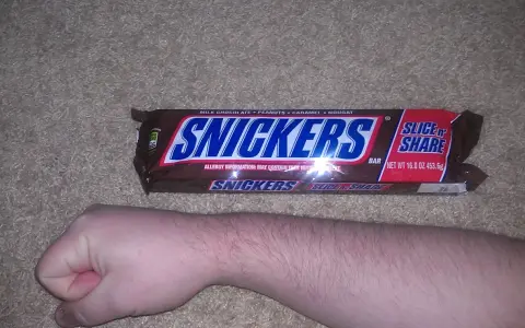 Opakowanie Snickers Slice 'n Share, obok ludzkiej ręki. Zastanawiasz się, snickers ile kalorii?