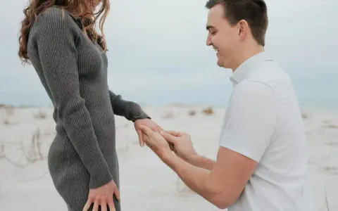 Mann macht Heiratsantrag am Strand. Ab wann darf man sich verloben? Das ist eine Frage der Liebe, nicht des Alters.