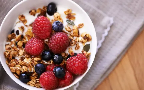 Un tazón de yogur con granola casera, frambuesas y arándanos. Un desayuno saludable y delicioso.
